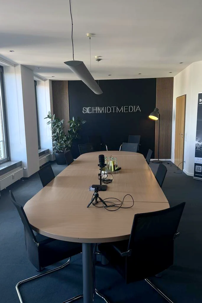 Blick in den Konferenzraum von schmidtmedia in Köln mit langem Besprechungstisch und Schriftzug an der Wand