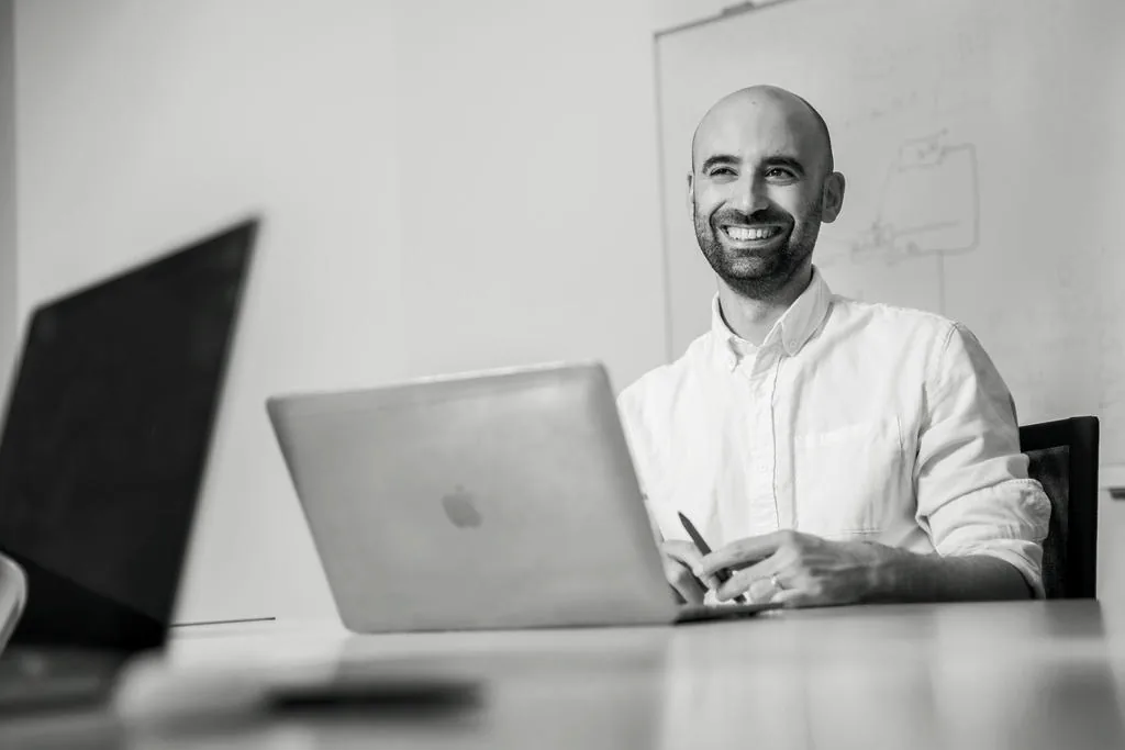 Mitarbeiter von schmidtmedia lacht am Arbeitsplatz vor dem Whiteboard