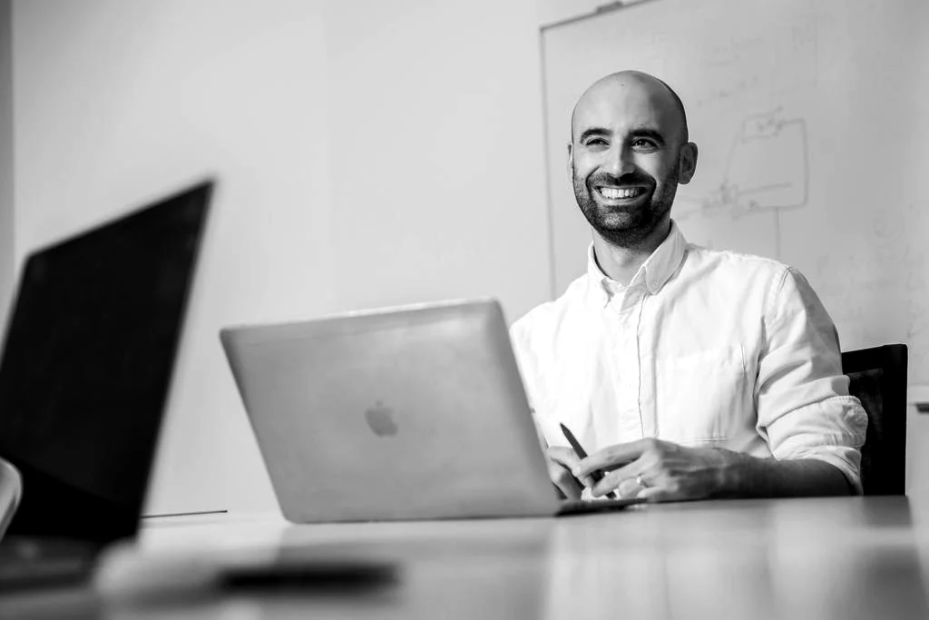 Mitarbeiter der Online-Marketing-Agentur schmidtmedia lacht am Arbeitsplatz vor dem Whiteboard