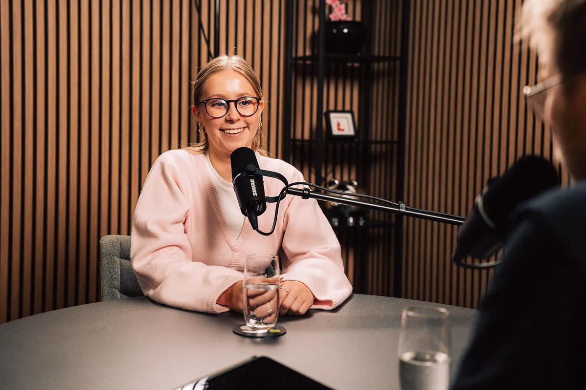 Lächelnde Gesprächspartnerin am Mikrofon bei einer Aufnahme des Podcasts „gründer & macher“ im Studio von schmidtmedia